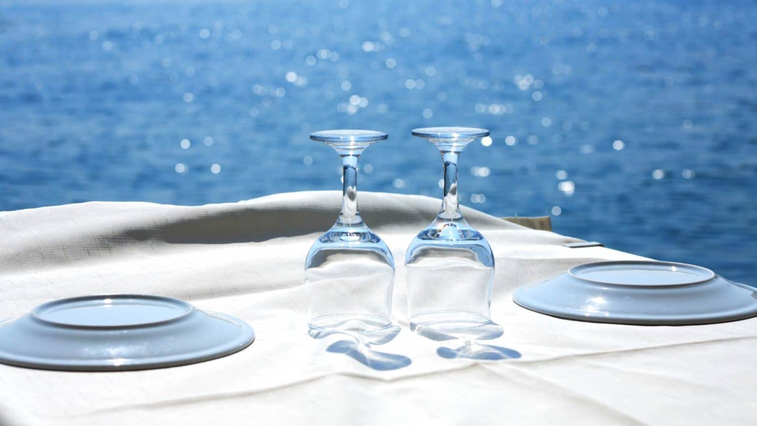 Tavolo con due bicchieri e due piatti sul mare
